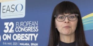 A woman with long dark hair and glasses speaks in front of a backdrop for the 32nd European Congress on Obesity, held in Malaga, Spain. Text on screen reads "Johanna Matilainen, Finland.